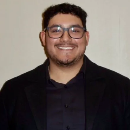 David Martinez, smiling, in glasses and a black blazer.